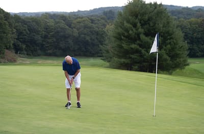 An older man putting on a golf course green
