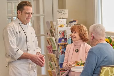 Chef engaging with residents at an indoor dining area