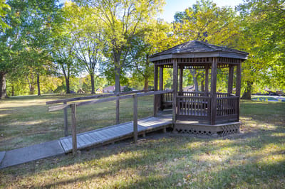 A wooden gazebo surrounded by trees in an outdoor space