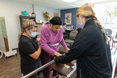 Staff assisting a resident with rehabilitation exercises
