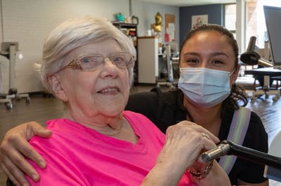 A staff member and resident smiling in an activity area