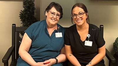 Two staff members smiling for a photo in the facility