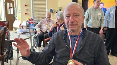 Resident celebrating with medals in a common area