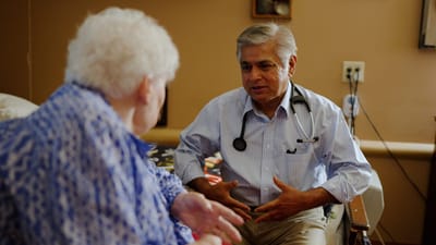 A doctor speaking with a female resident in a facility