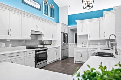 Bright, modern kitchen with white cabinets and blue accent wall