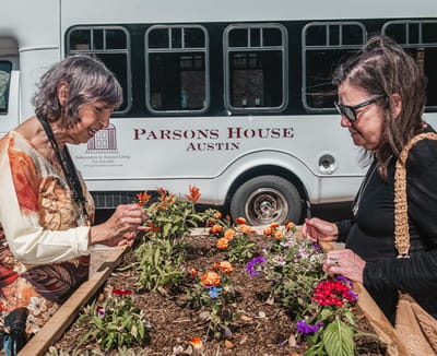 Two residents gardening near a facility bus