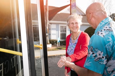A resident and staff member interacting near a transportation vehicle