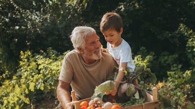 An elderly man and a young boy together in a garden