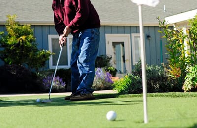 Resident practicing golf putting on a garden green
