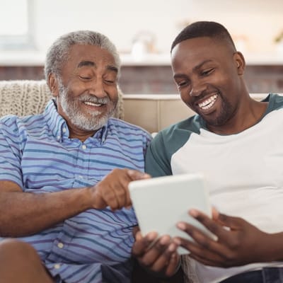 Two men sharing a light moment while viewing a tablet.