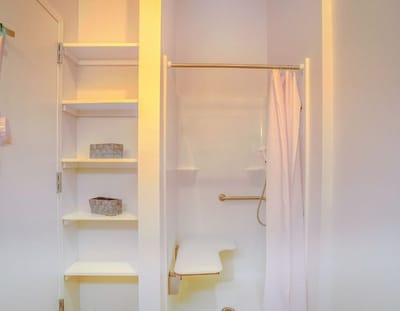A clean bathroom interior with shower and storage shelves
