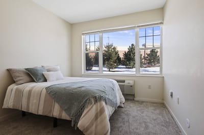 Brightly lit private resident room with a bed and window