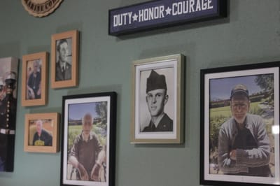 Framed military portraits and honor signage on a green wall