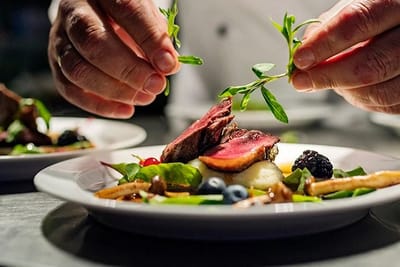 Chef plating gourmet meal with fresh ingredients