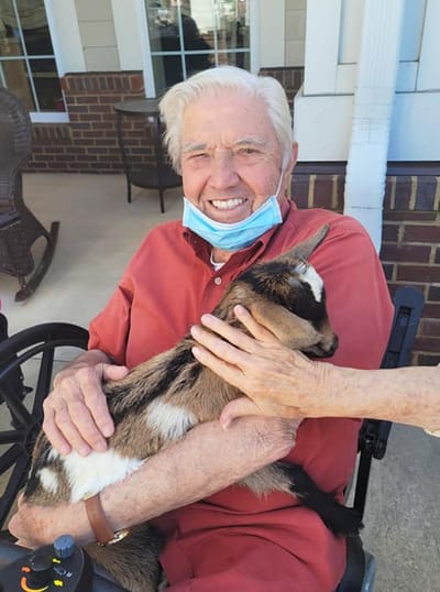 Resident smiling while holding a goat outside