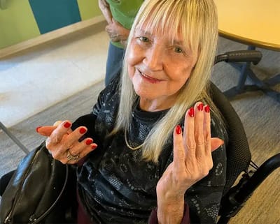 Resident showcasing freshly manicured nails in a vibrant activity room