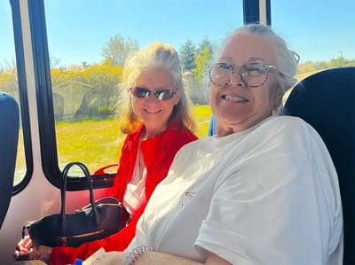 Two residents smiling on a bus outing