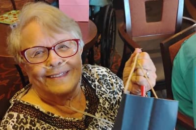 Resident smiling with a gift bag in a common area
