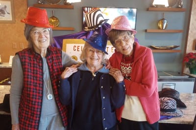 Three residents celebrating in festive hats inside the facility