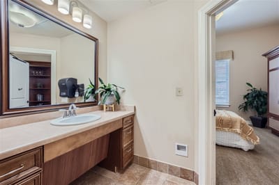 Brightly lit bathroom with a view of a bedroom.