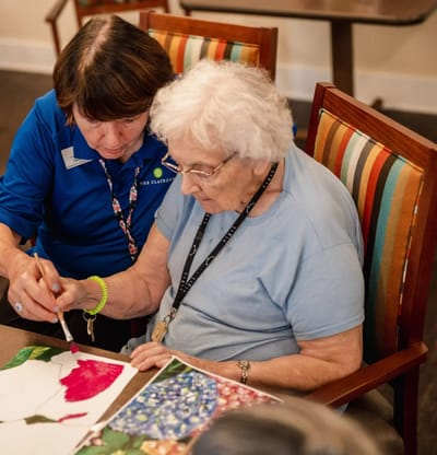 Staff assisting a resident with art activity