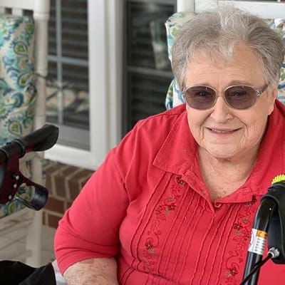 A resident smiling on a porch at Meadow View Senior Living Community