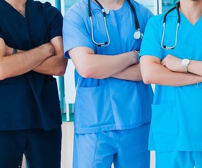 Healthcare professionals in scrubs with arms crossed.