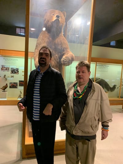 Two residents pose in front of a bear display.