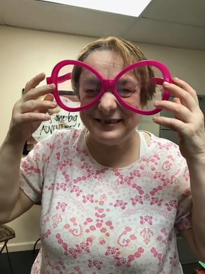 Resident wearing oversized pink glasses and smiling.