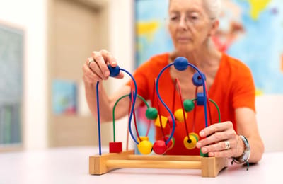 Senior woman playing with a children’s toy.