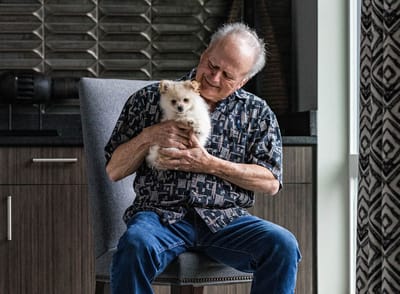 Resident joyfully holding a small dog indoors.