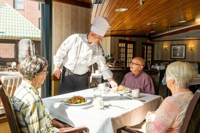 Chef serving food to residents in dining area