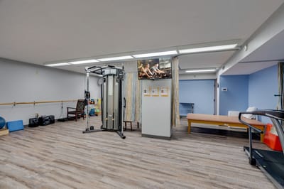 Exercise room with gym equipment and TV.