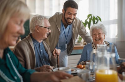 Happy residents and staff enjoying a meal together