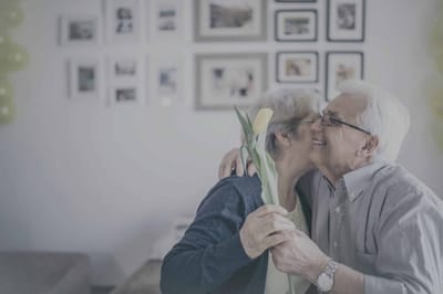 Elderly couple celebrating with a flower.