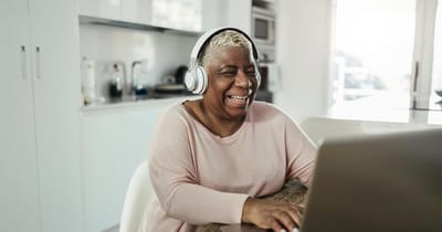 Senior woman smiling while using a laptop
