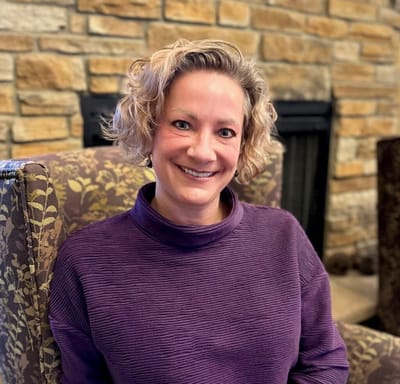 Staff member smiling in a cozy lounge area.