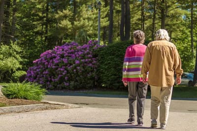 Two residents walking in a garden area