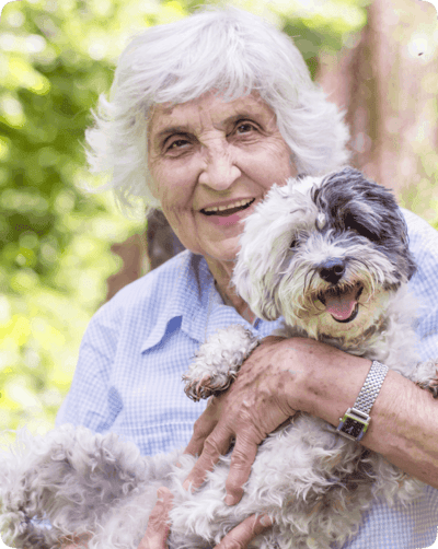 Senior woman happily holding a dog outdoors