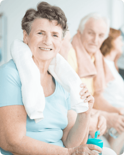 Happy senior woman with a towel, group in background.