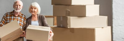 Older couple smiling with cardboard boxes.
