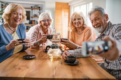 Seniors enjoying tea and conversation around a table.
