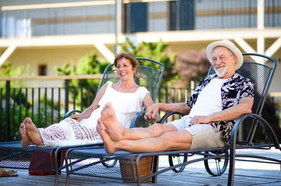 Two residents relaxing in lounge chairs outdoors.