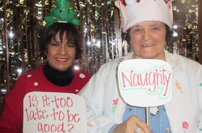 Two residents in festive outfits holding funny signs.