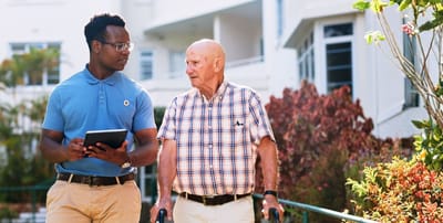 Caregiver assisting senior resident outdoors