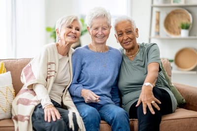 Three women smiling together on a couch