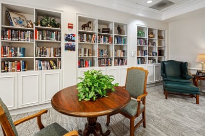 Cozy reading nook with bookshelves and plants.