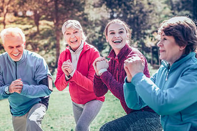 Four seniors exercising outdoors with staff