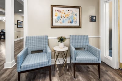 Cozy seating area with chairs and art on the wall.