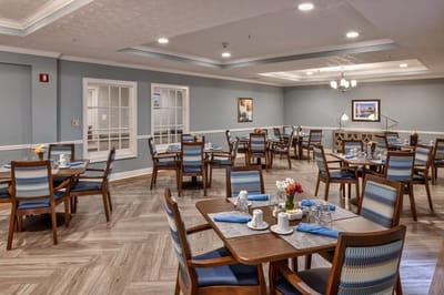 Dining room set up for residents with tables and flowers.